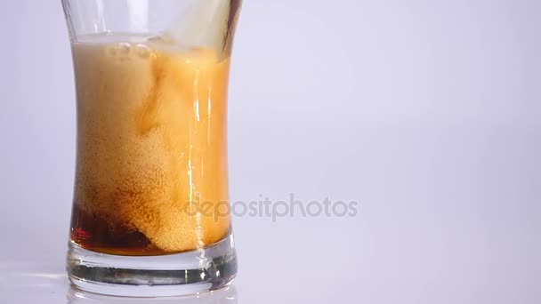 La cerveza se vierte en un vaso sobre fondo blanco con un manojo de trigo. Movimiento lento — Vídeo de stock