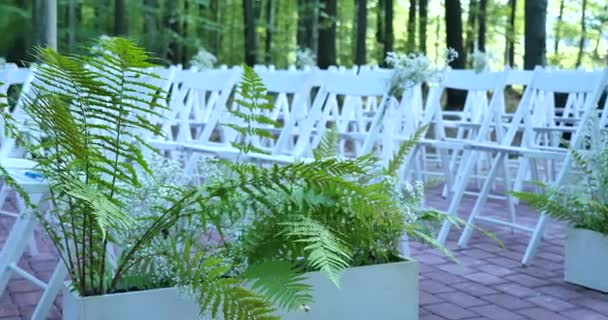 Sillas de boda blancas con flores. Ceremonia de boda exterior. Boda establecida en el jardín — Vídeo de stock