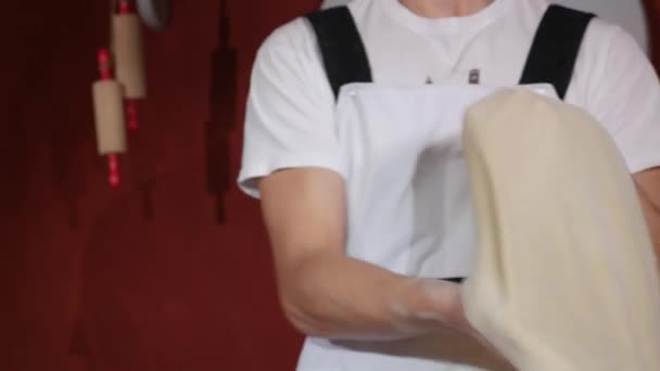 Mains du jeune homme filant et jetant de la pâte en l'air avec deux mains dans la cuisine du restaurant — Video