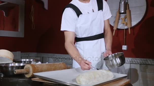 Young man covering raw strudel with stirred eggs — Stock Video