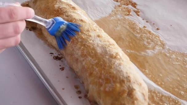 En ung man täcker en het strudel med olja — Stockvideo