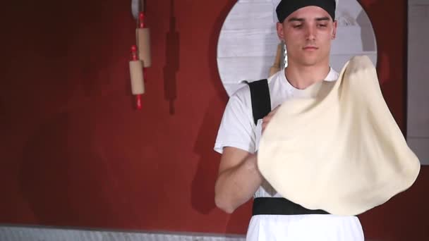 Młody człowiek, spinning i rzucanie ciasto się w powietrzu z dwoma ręce w kuchni w restauracji — Wideo stockowe
