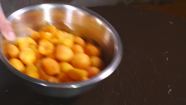 Le sucre tombe sur une assiette d'abricots sur une table en bois. gros plan — Video