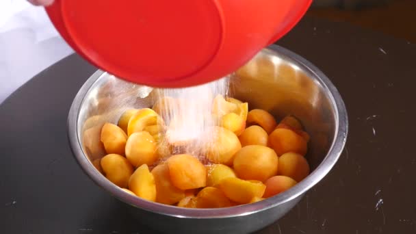 Sugar falls on a plate of apricots on a wood table. close up — Stock Video