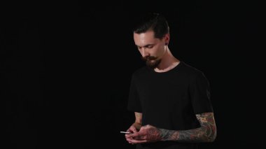 Sakallı bir adam cebinden telefonu alır ve bir ileti yazar