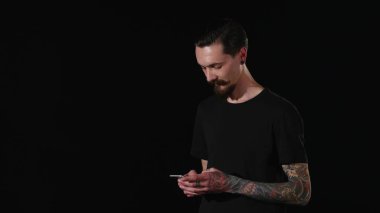 Sakallı bir adam cebinden telefonu alır ve bir ileti yazar