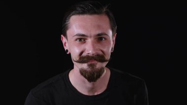 Sakallı adam bakar, gülümser ve kamera