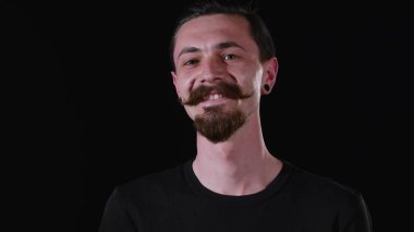 Sakallı adam bakar, gülümser ve kamera