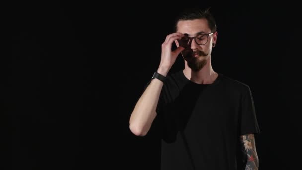 Бородатый парень снимает и одевает очки — стоковое видео