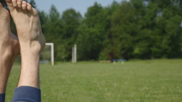 Mans pés em um fundo de árvores e grama. Uma pessoa feliz relaxando e tomando um banho de sol — Vídeo de Stock