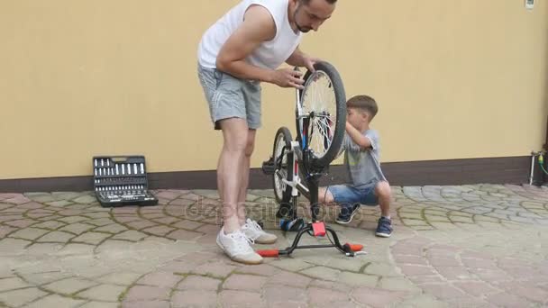 4k знімок батька і сина, що фіксує велосипед вдома — стокове відео
