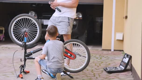 4k tiro de pai e filho fixando uma bicicleta em casa — Vídeo de Stock