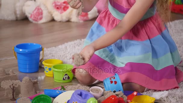 Hand süßes kleines blondes Mädchen, das in einem Studio Sand spielt. Nahaufnahme — Stockvideo