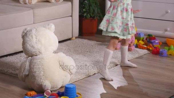 Bonne fille blonde dans la robe s'amuser à danser à l'intérieur dans une chambre blanche ensoleillée à la maison ou à la maternelle — Video