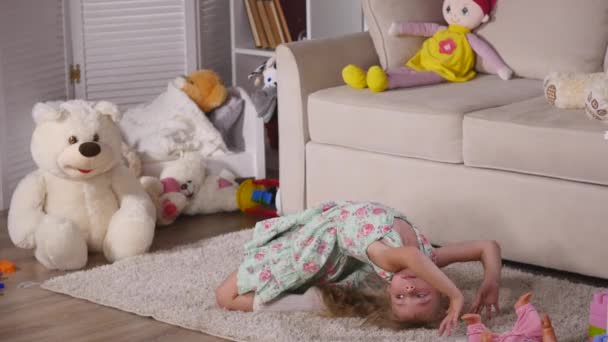 Een klein meisje, schattige jonge getalenteerde danser doet ballet houdingen en stretching oefeningen op de vloer thuis — Stockvideo