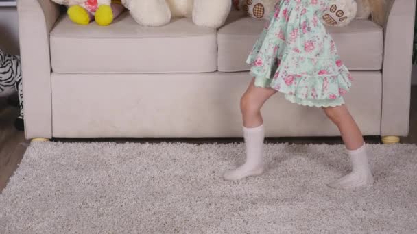 Bonne fille blonde dans la robe s'amuser à danser à l'intérieur dans une chambre blanche ensoleillée à la maison ou à la maternelle — Video