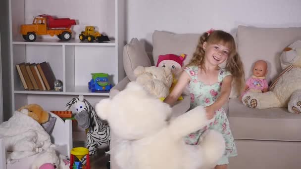 Uma menina gira com um urso branco no quarto. câmara lenta — Vídeo de Stock