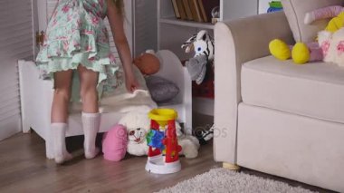 Etkin bir küçük okul öncesi çocuk, bir sarışın kıvırcık saçlı, sevimli küçük bir kız ile onun oyuncak bebek oyun, uyumaya yerleştirmektedir