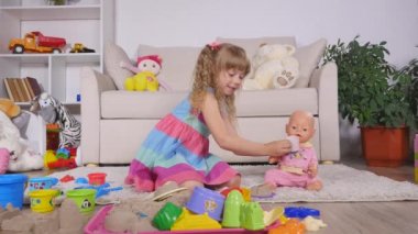 Çocuklar anne-kız Çal bir kız beslemeleri oyuncağın plastik kaşıkla adı gibi oyun oynarken