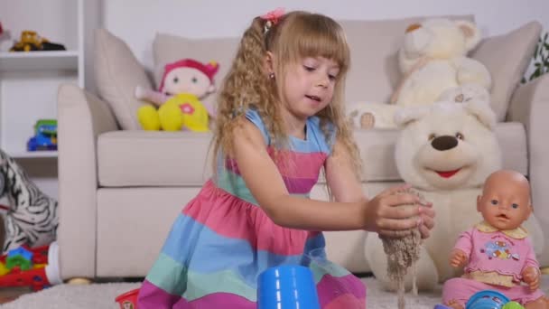 Petite fille blonde mignonne jouant au sable dans un studio — Video