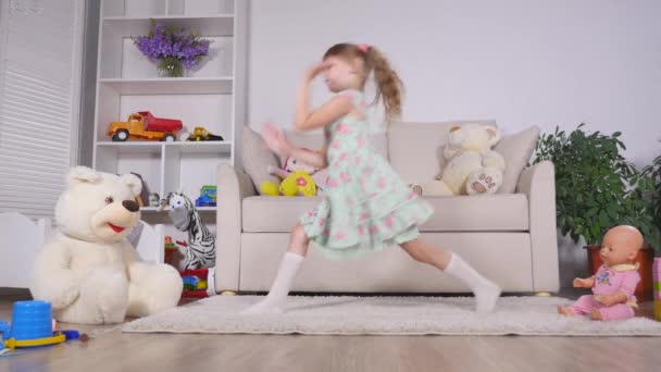 Ένα μικρό κορίτσι, κάνει αξιολάτρευτο νεαρός ταλαντούχος χορευτής μπαλέτου πόζες και διατατικές ασκήσεις στο πάτωμα στο σπίτι — Αρχείο Βίντεο