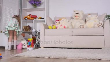 Etkin bir küçük okul öncesi çocuk, bir sarışın kıvırcık saçlı, sevimli küçük bir kız ile onun oyuncak bebek oyun, uyumaya yerleştirmektedir