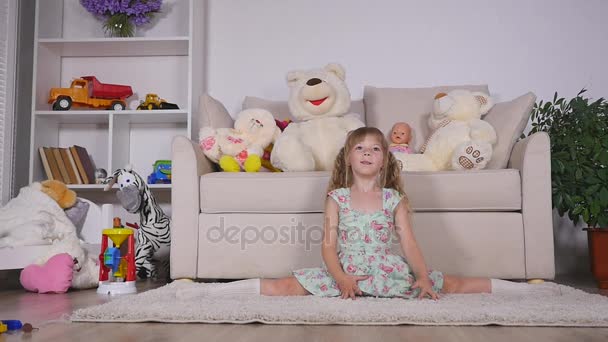 A little girl, adorable young talented dancer does ballet poses and stretching exercises on the floor at home — Stock Video