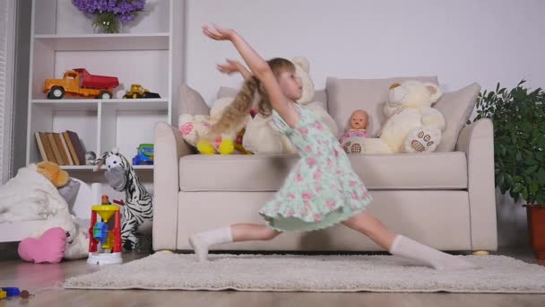A little girl, adorable young talented dancer does ballet poses and stretching exercises on the floor at home — Stock Video