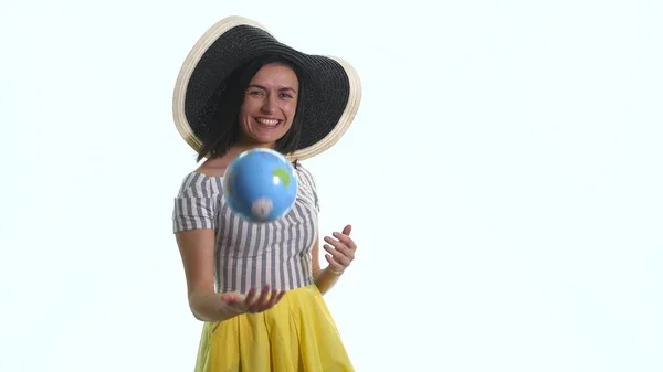 Uma jovem garota sorrindo está apontando para um globo contra um fundo branco — Fotografia de Stock