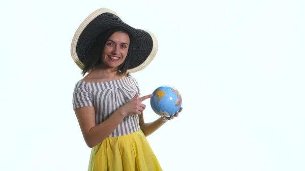 Uma jovem garota sorrindo está apontando para um globo contra um fundo branco — Fotografia de Stock