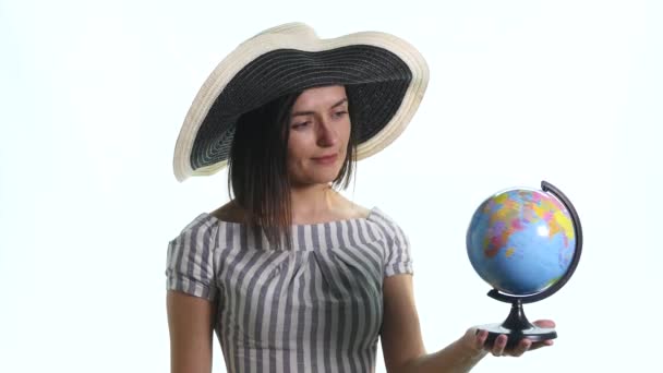 Een lachende meisje is wijzend op een wereldbol tegen een witte achtergrond — Stockvideo