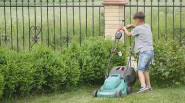 On yaşında bir çocuk büyük bir çim biçme makinesi ile çim biçme