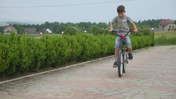 Дитячий велосипед - молодий хлопчик їде на велосипеді по дорозі — стокове відео