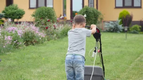 Tio-årig pojke gräsklippning med en stor gräsklippare — Stockvideo