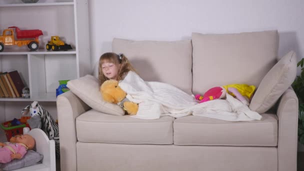 Όμορφο κοριτσάκι που ξαπλώνει στον καναπέ, πριν πάτε για ύπνο — Αρχείο Βίντεο