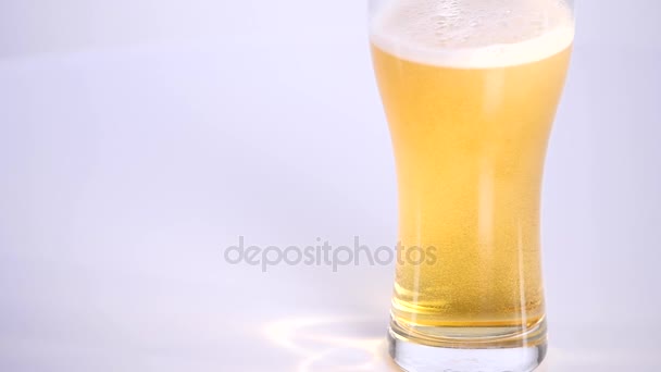 Glas Bier auf weißem Hintergrund mit eingelegten Erdnüssen — Stockvideo