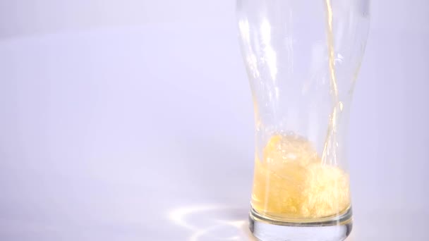 Bier ergießt sich in Glas auf weißem Hintergrund. Zeitlupe — Stockvideo