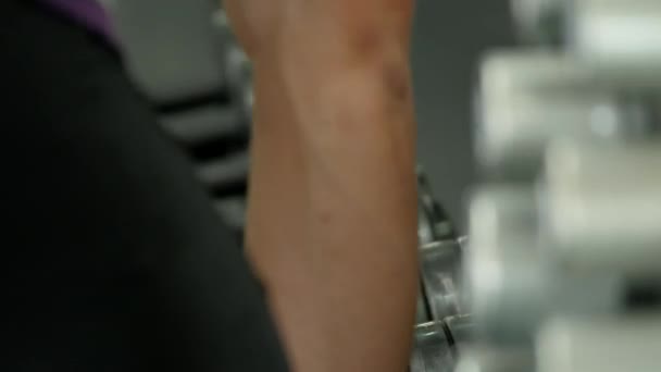 Man hands take dumbbells from gym stand, close up shot — Stock Video