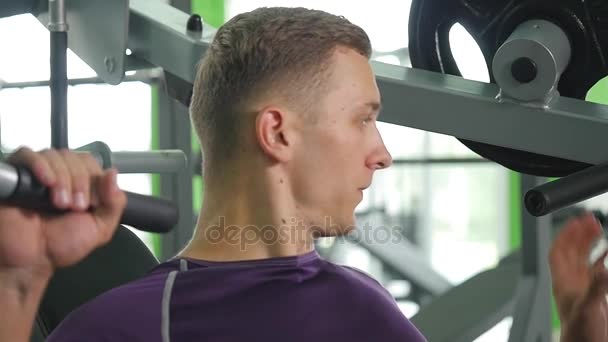 Hombre joven flexionando los músculos del pecho en la máquina de gimnasio — Vídeo de stock