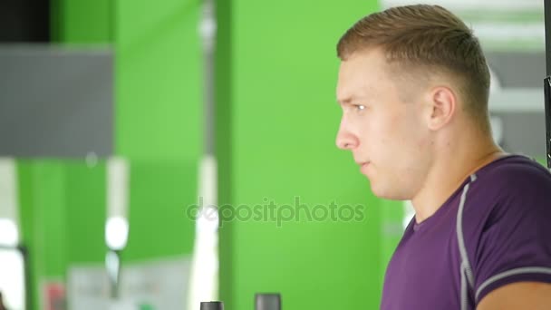 Umkippen eines jungen bärtigen Mannes mit nacktem Oberkörper beim Beinheben auf einer waagerechten Stange in einem Fitnessstudio — Stockvideo
