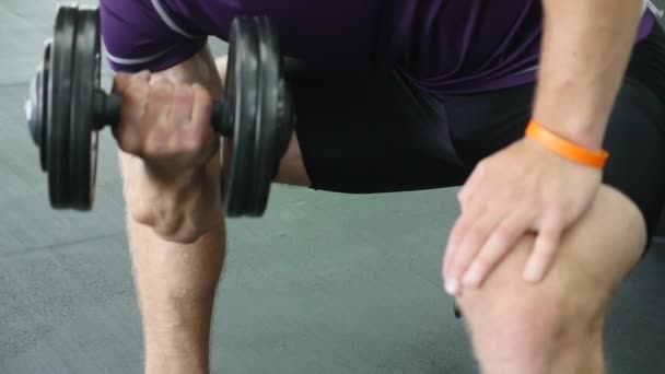 Mężczyzna pracujący ramiona na siłowni, on zniesienie dumbbells i pracy jego biceps — Wideo stockowe