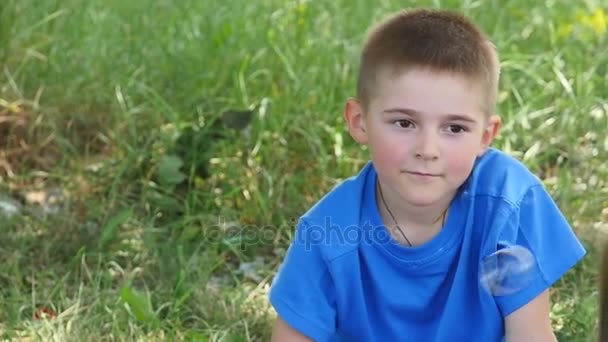 Niño feliz soplando burbujas de jabón en el parque de primavera. Movimiento lento — Vídeos de Stock