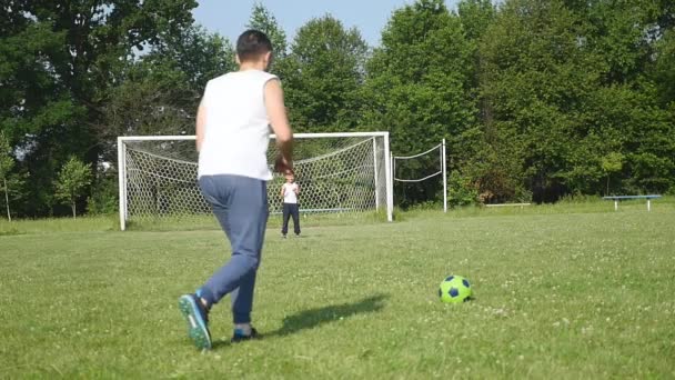 Far och son som spelar fotboll på fotbollen på dagtid — Stockvideo