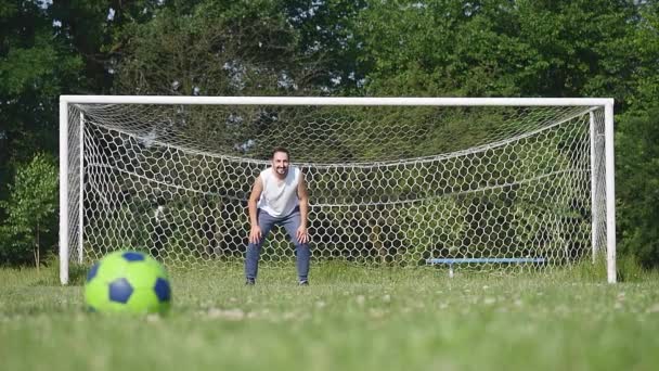 Far och son som spelar fotboll på fotbollen på dagtid — Stockvideo