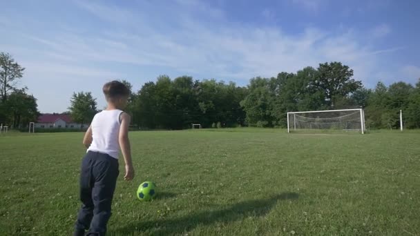 Мальчик играет в футбол на футбольном поле. замедленное движение — стоковое видео