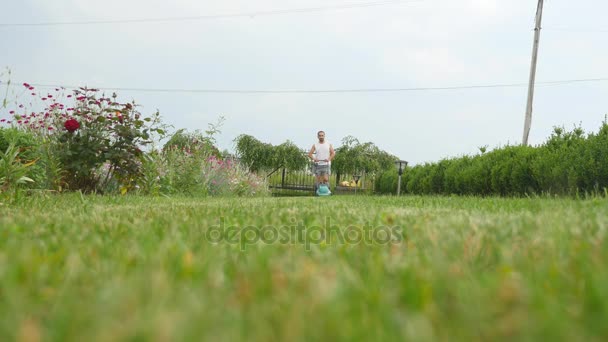 Mann mäht Gartenrasen mit Mähmaschine im Hof — Stockvideo