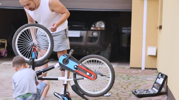 Vater und Sohn reparieren an einem sonnigen Tag ein Fahrrad — Stockvideo