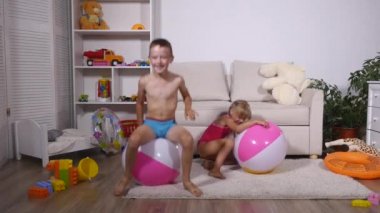 Çocuk iyi eğlenceler oturmak ve büyük lastik şişme top oyun odası atlamak