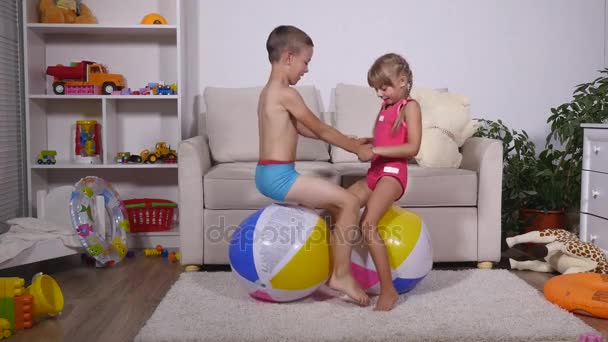 Дети весело сидеть и прыгать на больших резиновых надувных шариков в игровой комнате — стоковое видео