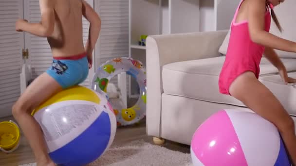 I bambini si divertono a sedersi e saltare su grandi palle gonfiabili in gomma nella sala giochi — Video Stock